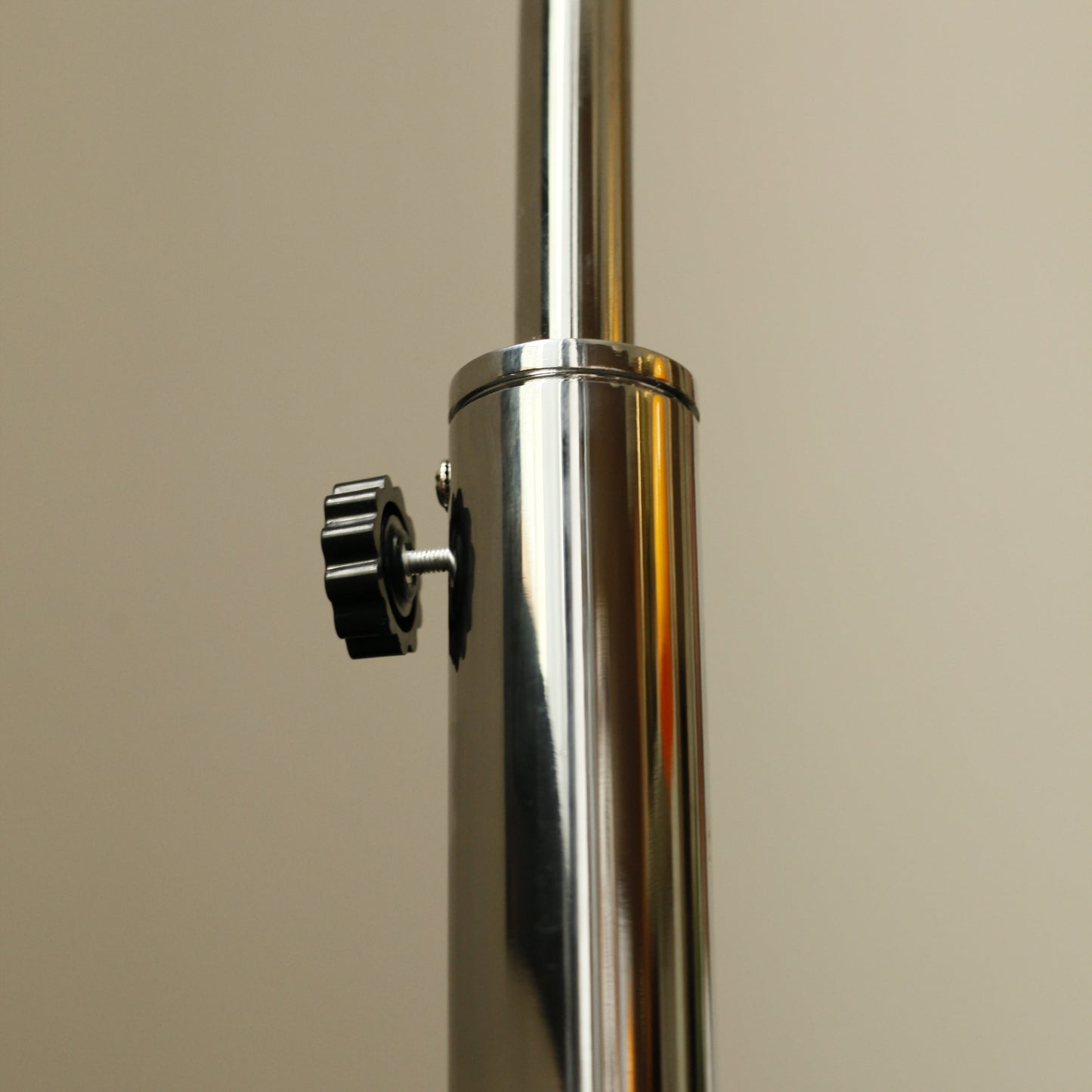 Detail of chrome arch arm on Orange Arch Lamp reflecting natural light